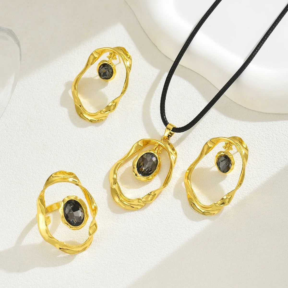 Gold-tone irregular hoop earrings and matching pendant necklace with dark smoky quartz stones.