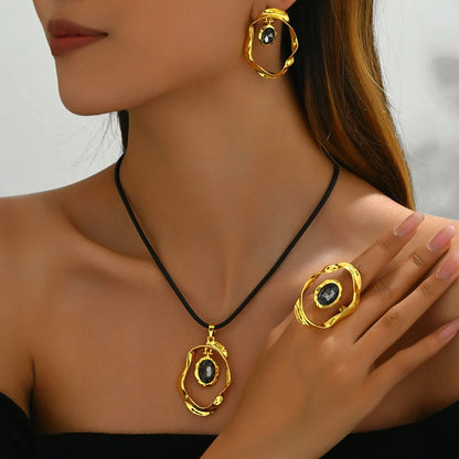 Gold textured earrings, necklace, and ring set with dark gemstone accents