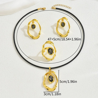 Gold-toned jewelry set featuring an irregular oval necklace, ring, and earrings with dark gemstones.